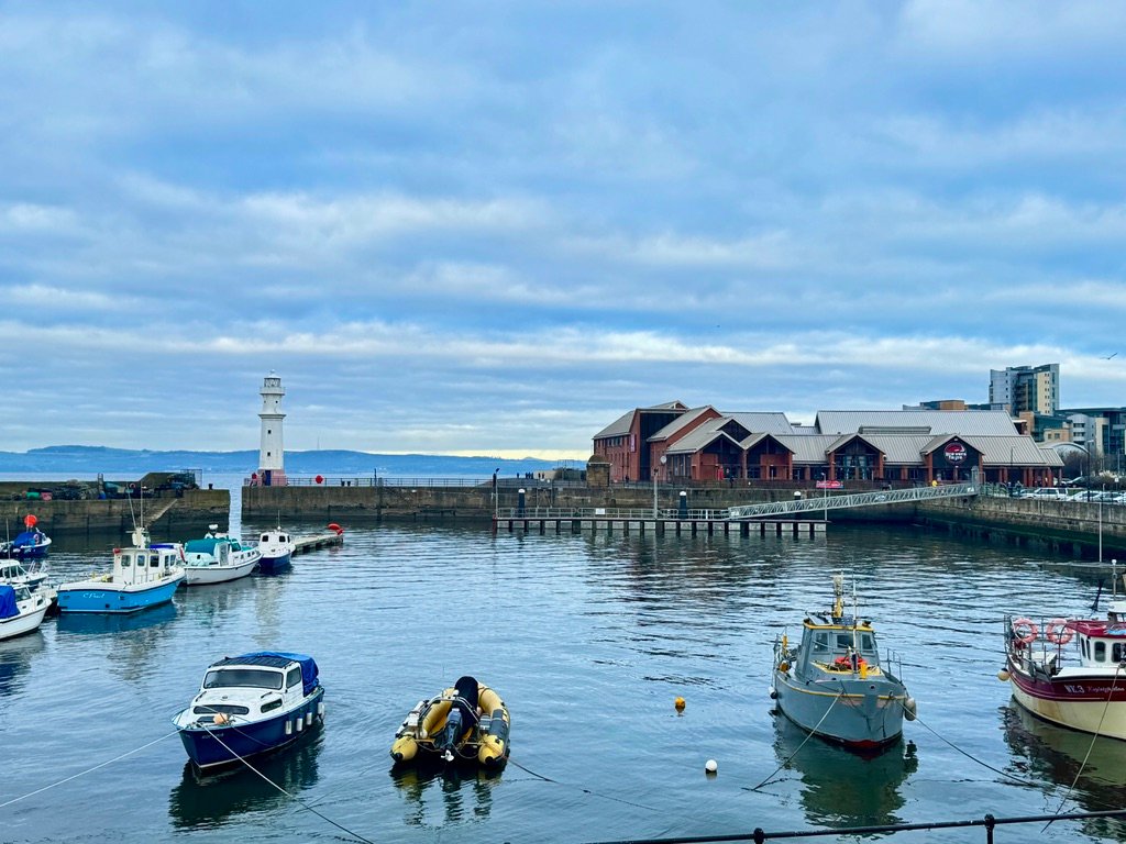 Newhaven Harbour Fishing boats moored in Newhaven Harbour, Edinburgh, with a lighthouse and waterfront buildings in the background