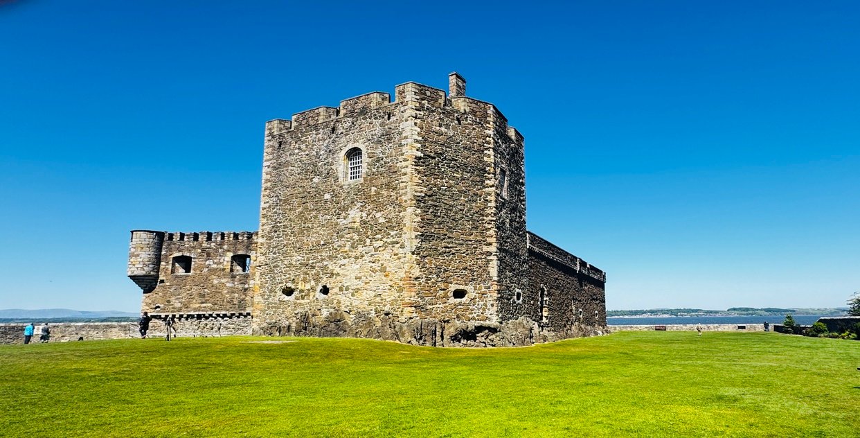 Blackness Castle's stone tower on the Firth of Forth, set on a green lawn under a clear blue sky