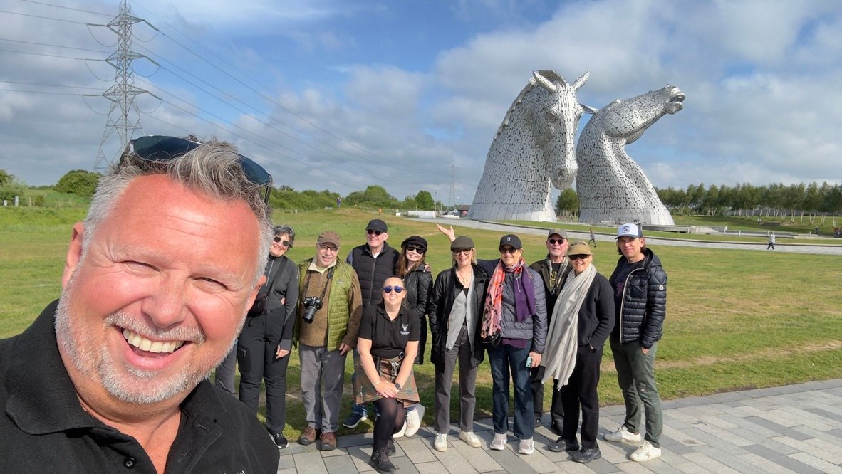 Group Photo at the Kelpies A tour group posing for a selfie in front of the Kelpies sculptures in Falkirk on a sunny day