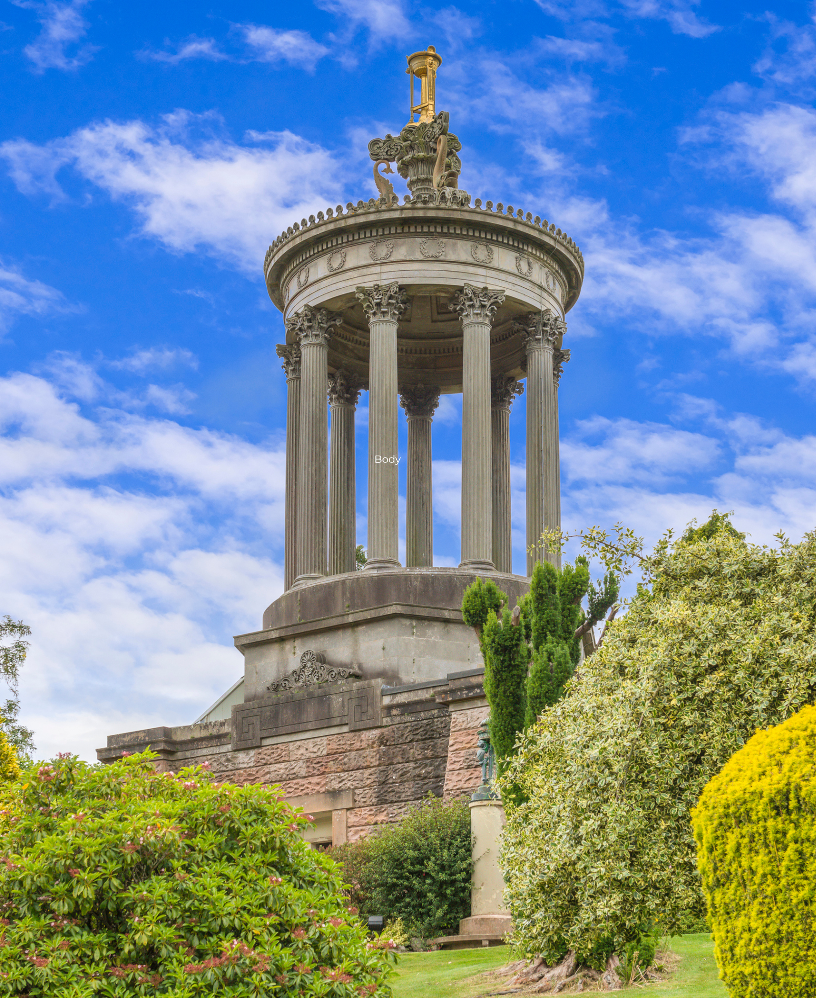 The Burns Monument, a Corinthian-columned circular temple in Alloway, surrounded by gardens under a blue sky