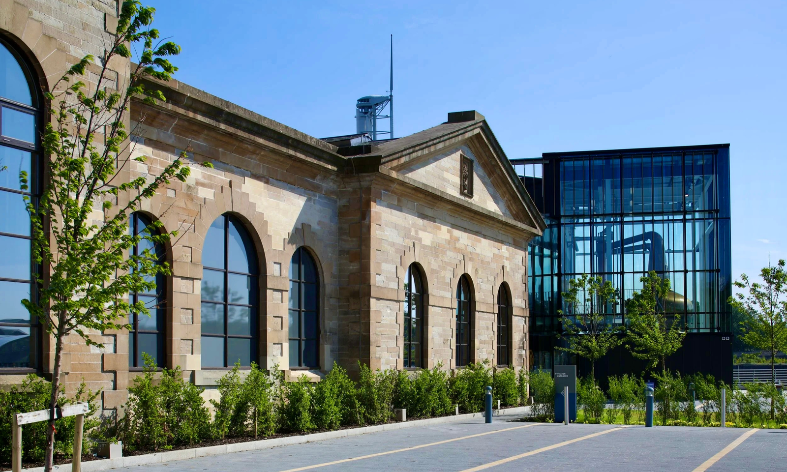 The Clydeside Distillery The Clydeside Distillery's sandstone pump house building beside its modern glass extension, with a copper still visible through the windows
