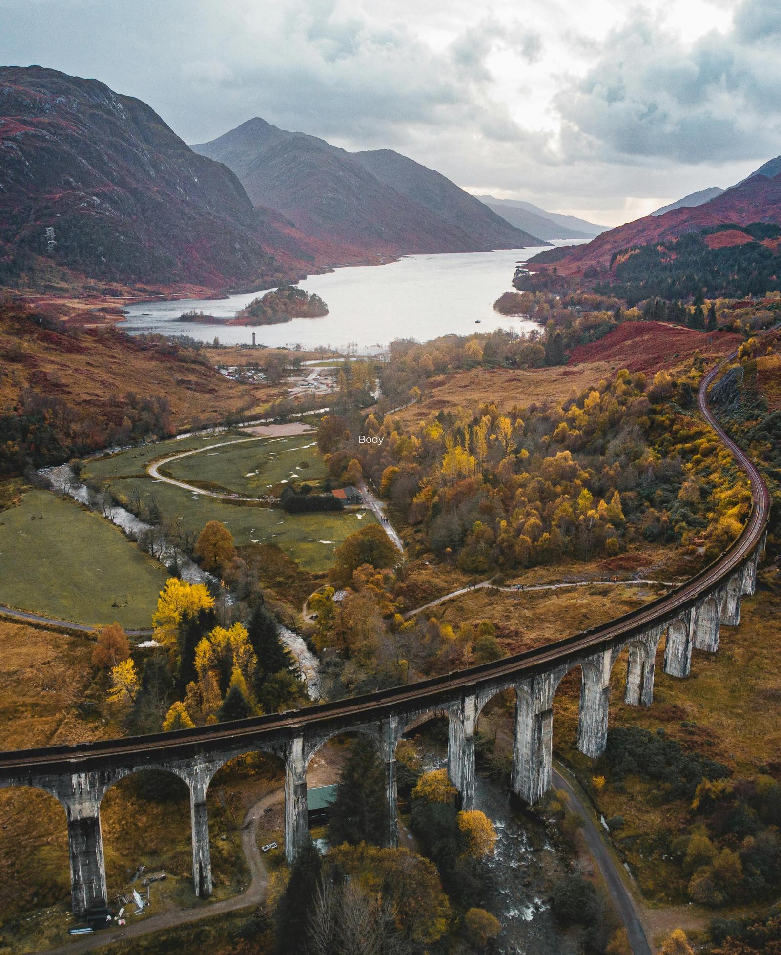 The Glenfinnan Viaduct curving through the Scottish Highlands, with Loch Shiel and autumn-coloured hills in the background