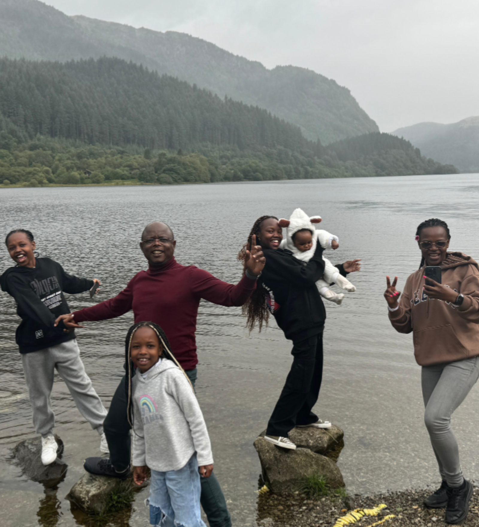 Family enjoying private tour at Loch Lomond Happy family posing on rocks at the shore of Loch Lomond, Scotland