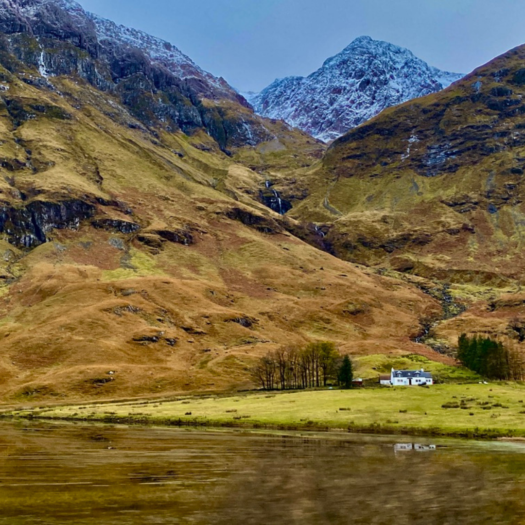 Cottage Beneath the Mountains, Glencoe Remote white cottage against snow-capped peaks in Glencoe, Scotland