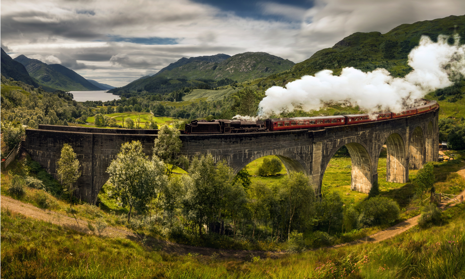 The Jacobite steam train crossing the Glenfinnan Viaduct, with Loch Shiel and the Highlands in the background