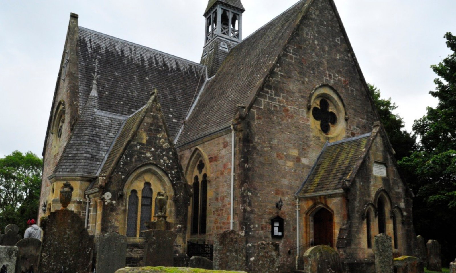 Luss Parish Church with its stone gables and bell tower, surrounded by weathered gravestones
