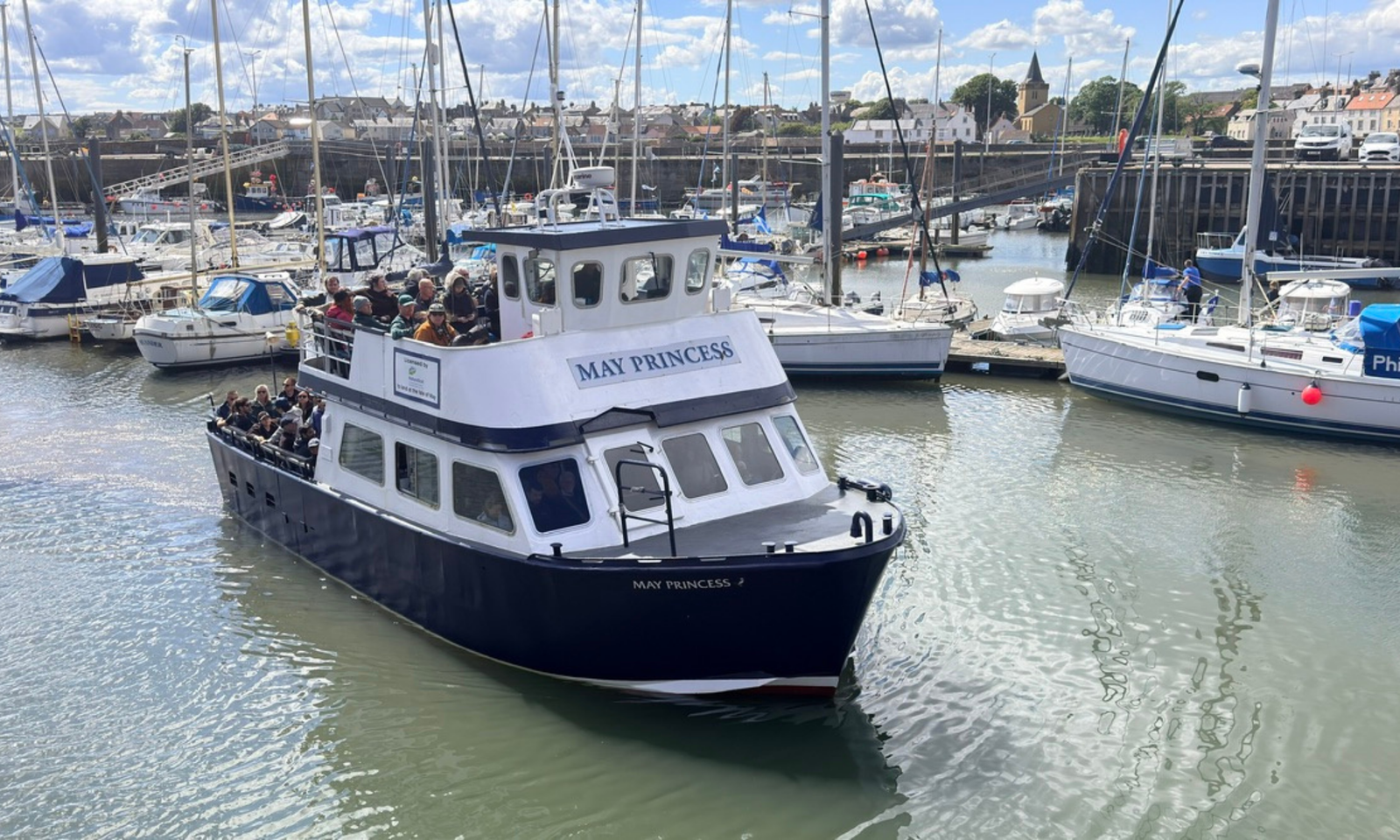 May Princess Boat at Anstruther Harbour The May Princess tour boat carrying passengers through Anstruther Harbour, with the town and marina behind