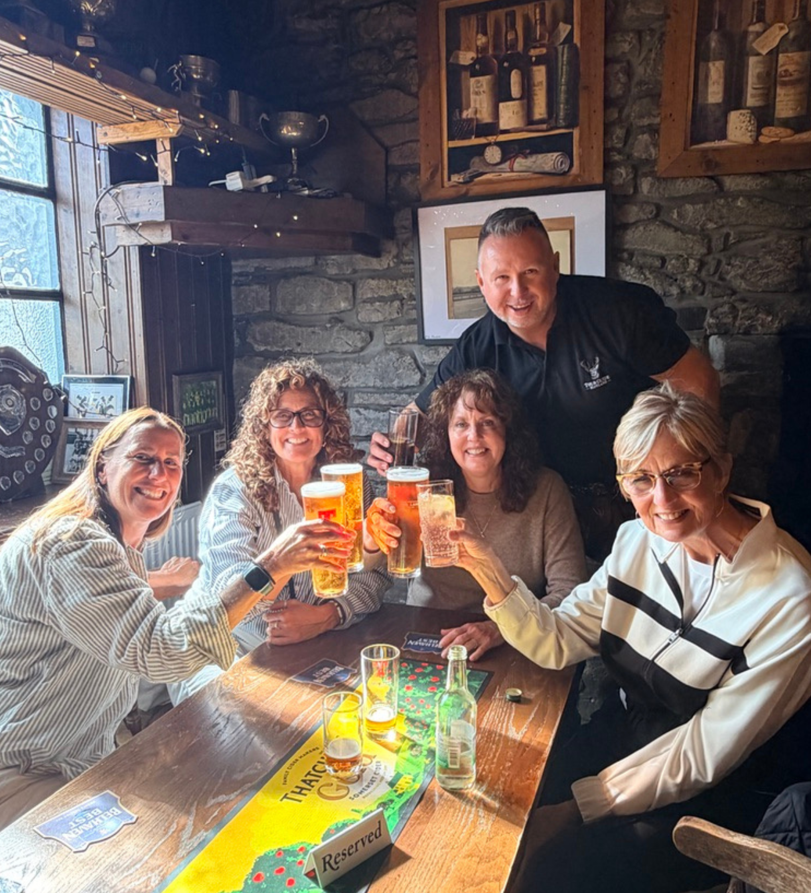 Guests raising a toast in a Scottish country pub Happy guests toasting drinks at a traditional Scottish pub