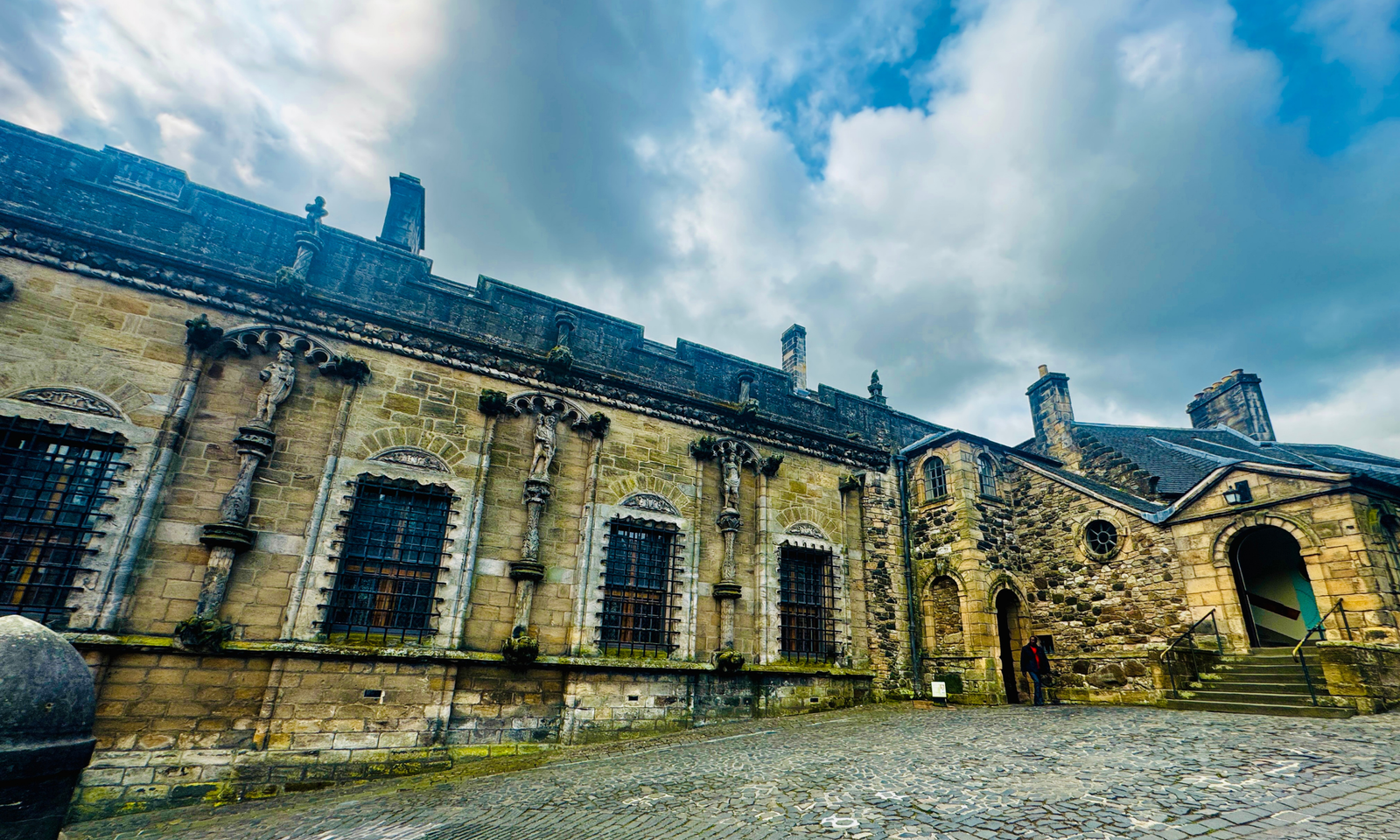 Stirling Castle Royal Palace Exterior The ornately carved exterior of Stirling Castle's Royal Palace, with statue niches and barred windows above a cobbled courtyard
