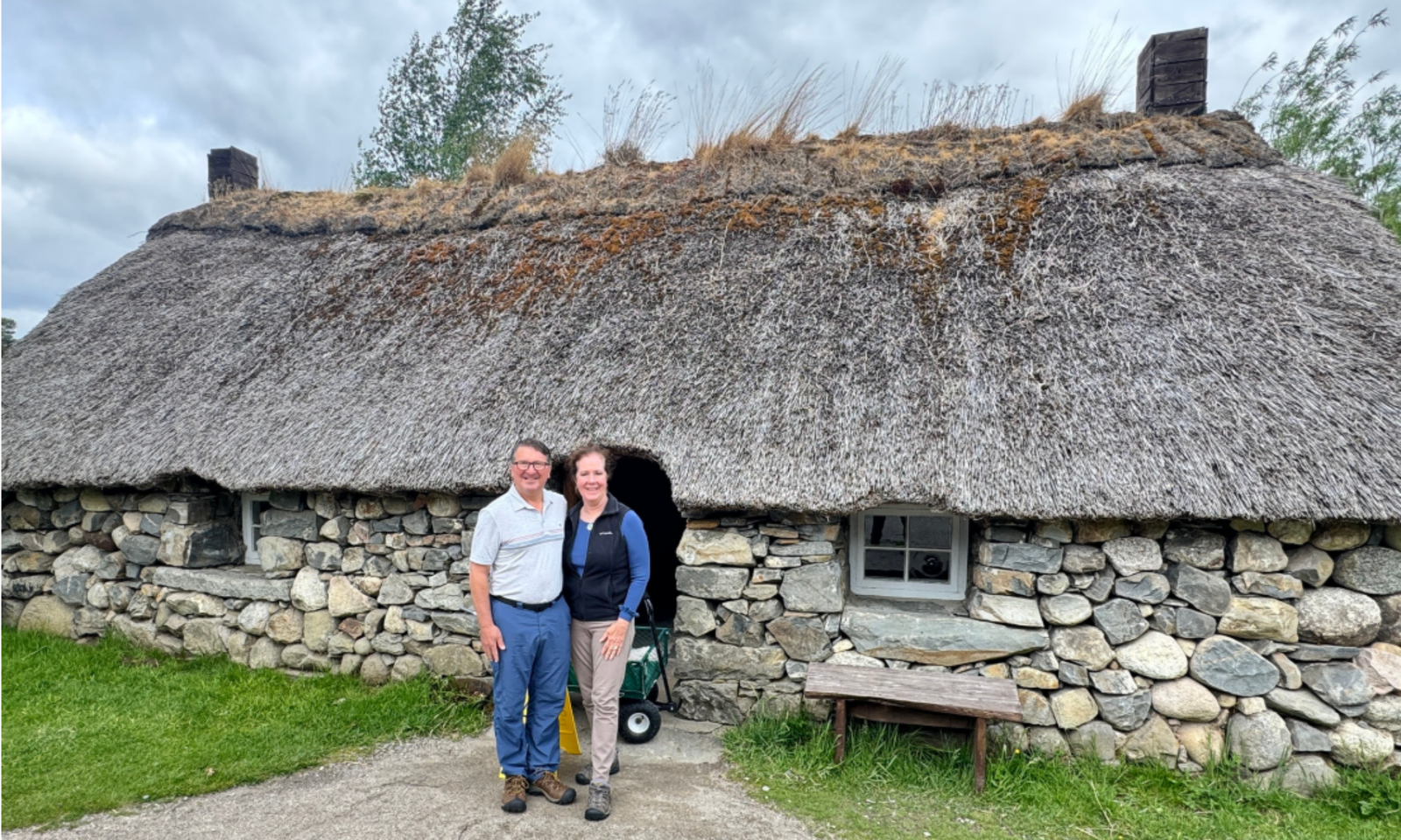 The Highland Folk Museum Visitors standing outside a traditional thatched-roof stone cottage at the Highland Folk Museum