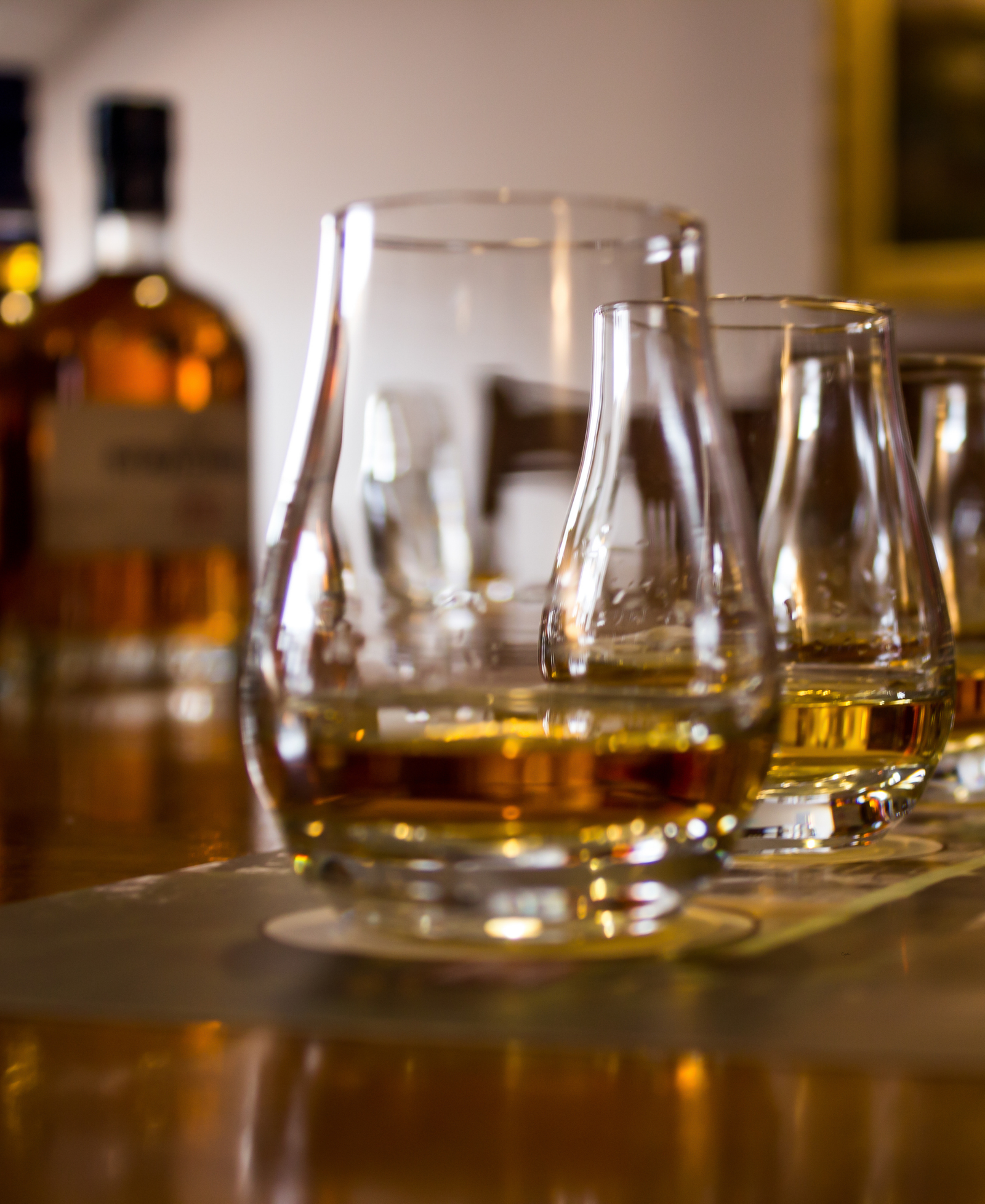 Whisky Tasting Glencairn glasses of whisky lined up on a bar with a whisky bottle in the background