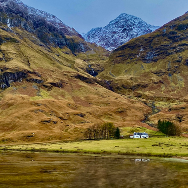 Cottage Beneath the Mountains, Glencoe Remote white cottage against snow-capped peaks in Glencoe, Scotland